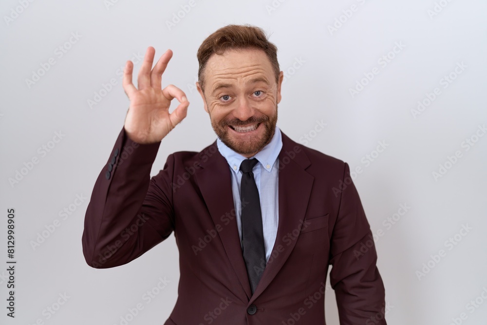 Middle age business man with beard wearing suit and tie smiling positive doing ok sign with hand and fingers. successful expression. Middle age business man with beard wearing suit and tie smiling positive doing ok sign with hand and fingers. successful expression.