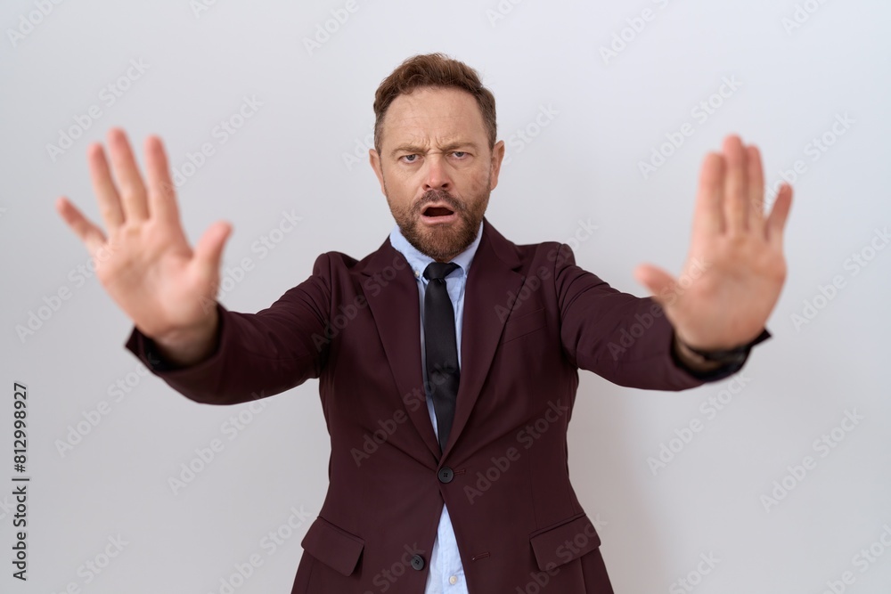 Middle age business man with beard wearing suit and tie doing stop gesture with hands palms, angry and frustration expression Middle age business man with beard wearing suit and tie doing stop gesture with hands palms, angry and frustration expression