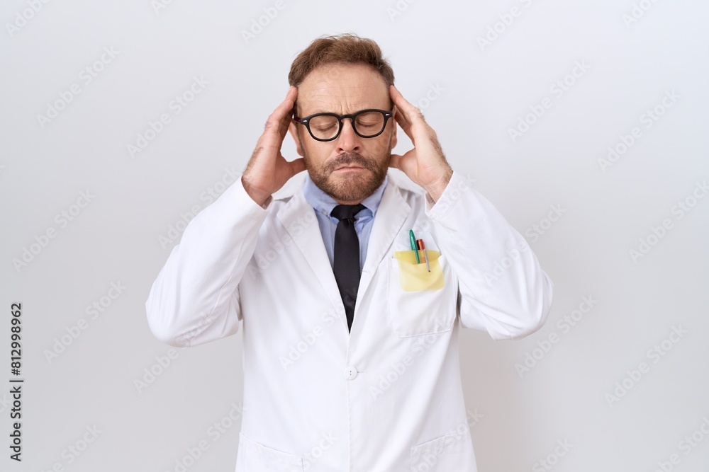 Middle age doctor man with beard wearing white coat with hand on head for pain in head because stress. suffering migraine. Middle age doctor man with beard wearing white coat with hand on head for pain in head because stress. suffering migraine.