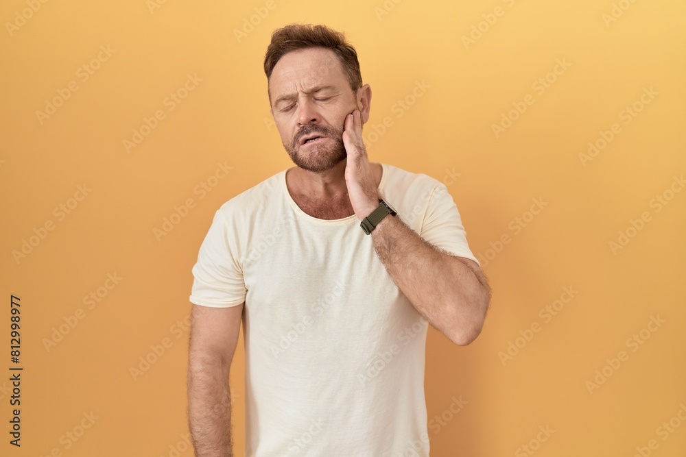 Middle age man with beard standing over yellow background touching mouth with hand with painful expression because of toothache or dental illness on teeth. dentist Middle age man with beard standing over yellow background touching mouth with hand with painful expression because of toothache or dental illness on teeth. dentist