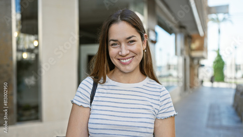 A smiling woman with blue eyes and brunette hair enjoys a sunny day outdoor in the city. Free Download A smiling woman with blue eyes and brunette hair enjoys a sunny day outdoor in the city. - GFXLoad