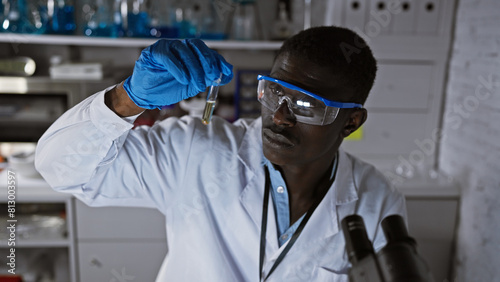 African man in lab coat examining test tube in a laboratory setting, portraying medical or scientific research.