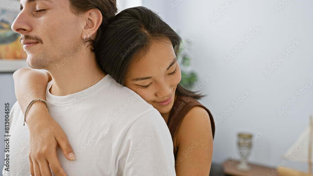 Intimate couple, asian woman, and hispanic man, embracing softly in a cozy apartment living room. Intimate couple, asian woman, and hispanic man, embracing softly in a cozy apartment living room.