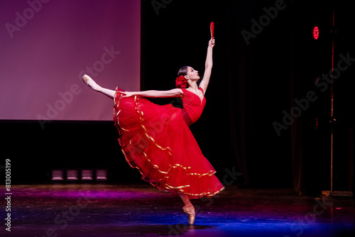 Photos ballerina in a red dress performs a variation from the ballet Don Quixote on the theater stage