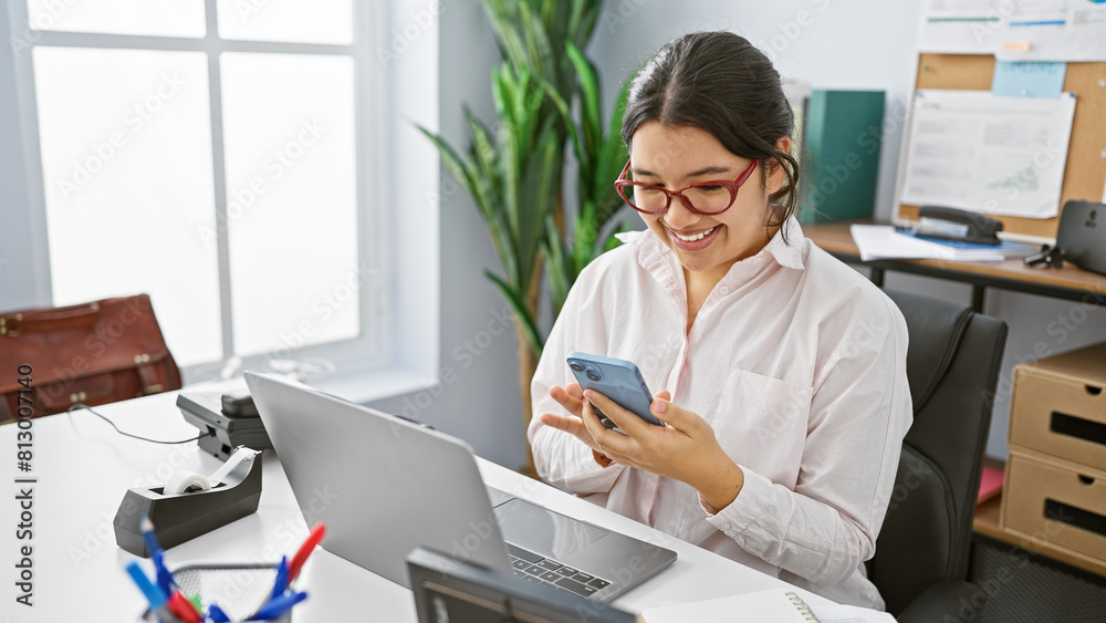 Smiling hispanic woman using smartphone in modern office, portraying connectivity and workplace productivity. Smiling hispanic woman using smartphone in modern office, portraying connectivity and workplace productivity.
