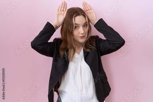Young caucasian business woman wearing black jacket doing bunny ears gesture with hands palms looking cynical and skeptical. easter rabbit concept. photo