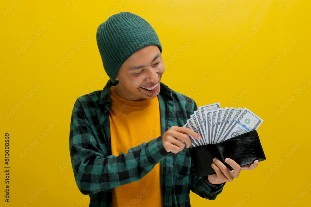 Thoughtful Asian man holds a wallet filled with cash contemplating how to spend it wisely, focusing on potential investments and ways to increase earnings. Business, finance, and saving money concept Thoughtful Asian man holds a wallet filled with cash contemplating how to spend it wisely, focusing on potential investments and ways to increase earnings. Business, finance, and saving money concept
