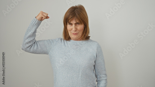 Confident middle-aged woman flexing her arm muscle against a white background, showcasing strength and positivity.