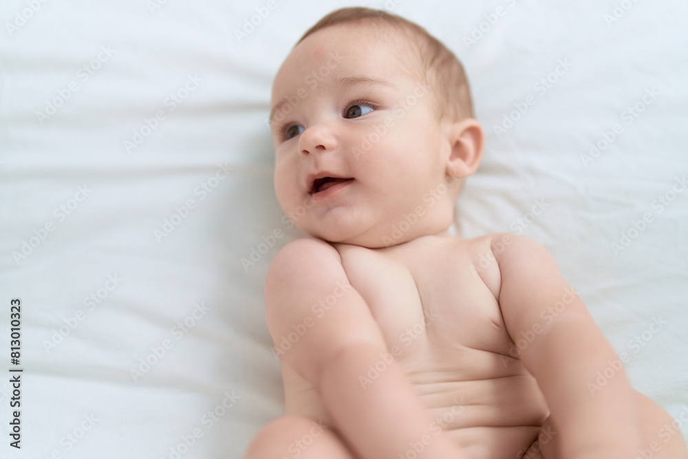 Adorable toddler lying on bed with relaxed expression at bedroom Adorable toddler lying on bed with relaxed expression at bedroom