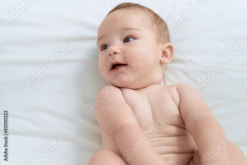 Adorable toddler lying on bed with relaxed expression at bedroom