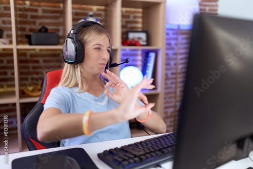 Young caucasian woman playing video games wearing headphones disgusted expression, displeased and fearful doing disgust face because aversion reaction. photo