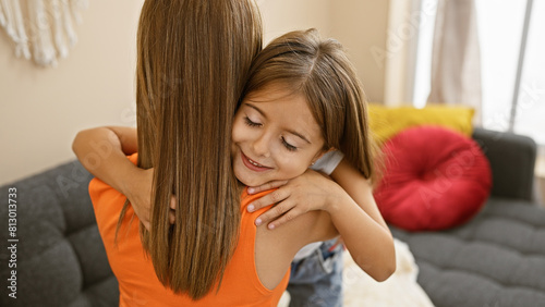 A smiling girl embraces her mother in a cozy living room, reflecting family, love, and a happy home atmosphere.