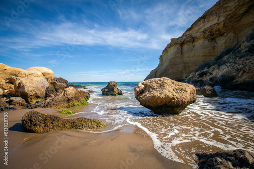 View of the small Cala Rosas in the Puntas de Calnegre regional park in the Region of Murcia with large rocks at the water's edge