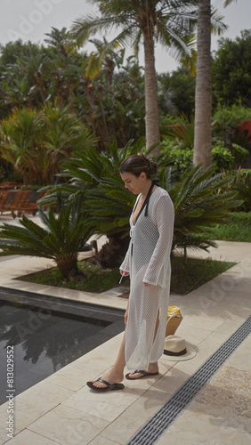 Serene woman in a coverup walks by a pool in a lush bali resort, embodying tropical relaxation and luxury. photo