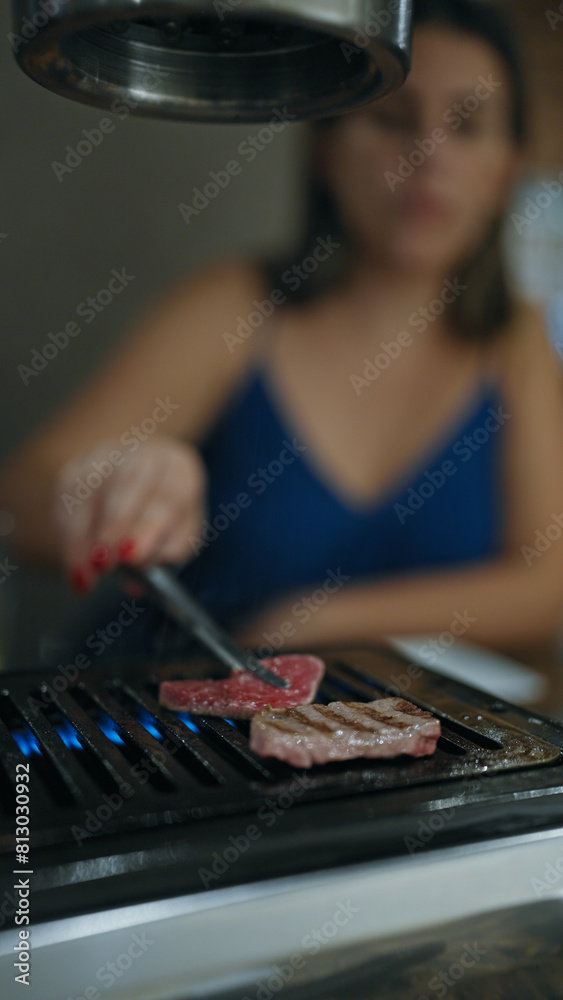 Modern dining experience, young woman's hands cook delicious, rare wagyu beef on grill in japanese restaurant, savoring the juicy roasted meat