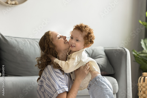 Happy caring young mom hugging cute red haired toddler son at home, playing with child on floor, cuddling, kissing cheerful kid, expressing love, affection, care, enjoying family mothers leisure © fizkes