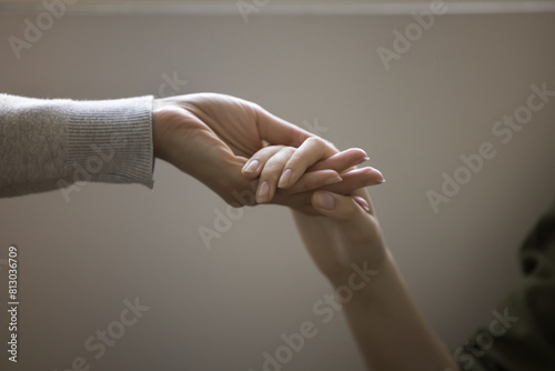 Woman and teenager girl holding hands close up cropped shot. Adult person, psychotherapist, mother giving support, care, compassion to young teen kid, helping to cope with depression, problem