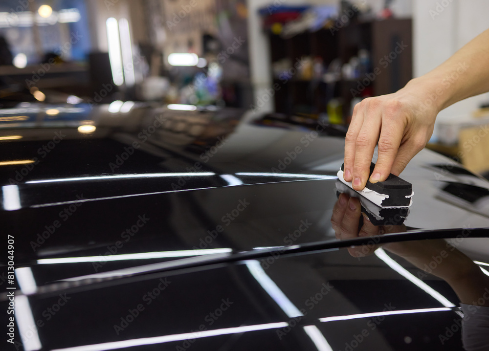 Hand gestures polishing black car hood with sponge Hand gestures polishing black car hood with sponge