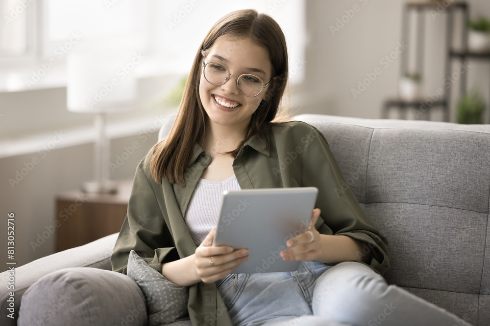 Happy beautiful school student, teenage kid girl using tablet at home for education, communication, holding digital device, relaxing on home sofa, looking away, smiling, thinking Happy beautiful school student, teenage kid girl using tablet at home for education, communication, holding digital device, relaxing on home sofa, looking away, smiling, thinking