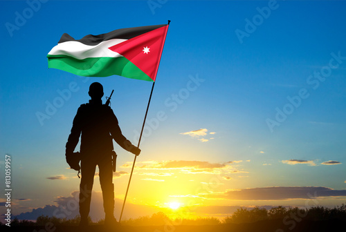 Silhouette of a soldier holding a Jordanian flag against the sunset