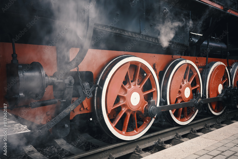 Naklejka premium Close-up of a steam locomotive wheel at a railway station.