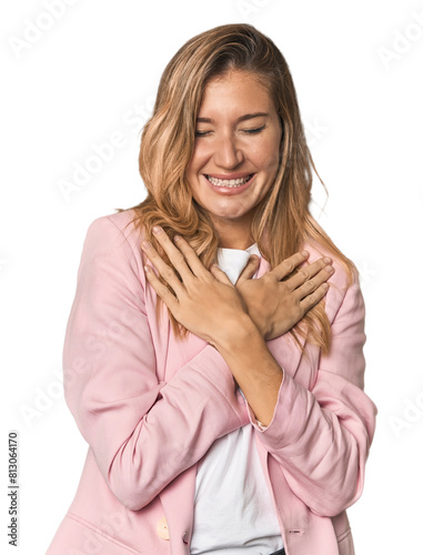 Young blonde in stylish pink suit laughing keeping hands on heart, concept of happiness.