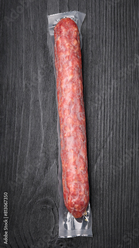 Vacuum packed salami sausage on wooden background photo