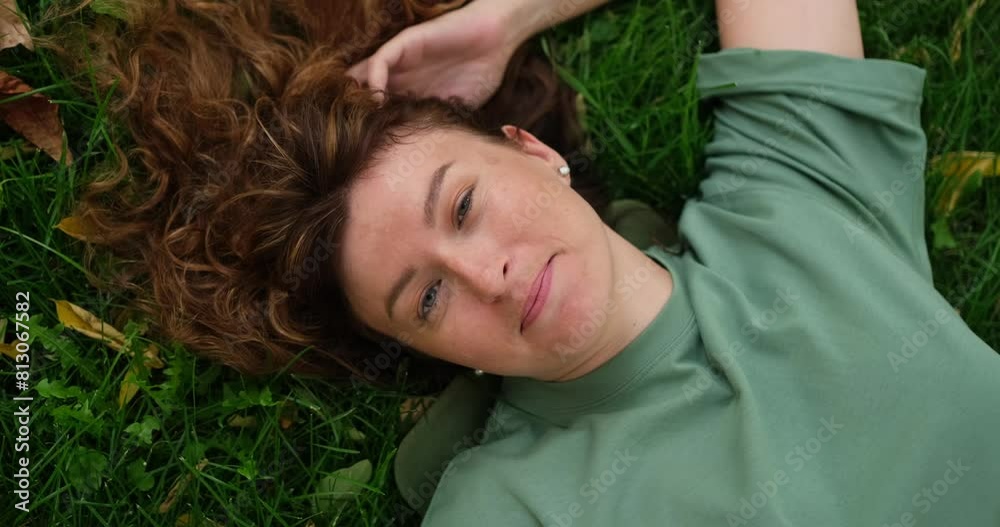 Closeup redhead girl lying on green grass with different emotions, from happiness to sadness. Beautiful woman at sunny summer in park outdoors lying and making expressions with face and hands Closeup redhead girl lying on green grass with different emotions, from happiness to sadness. Beautiful woman at sunny summer in park outdoors lying and making expressions with face and hands