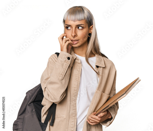 Caucasian young student with books biting fingernails, nervous and very anxious.