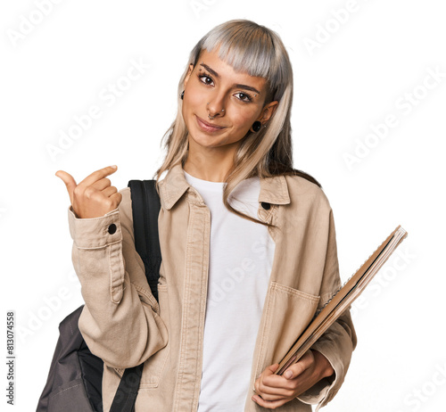 Caucasian young student with books pointing with finger at you as if inviting come closer.