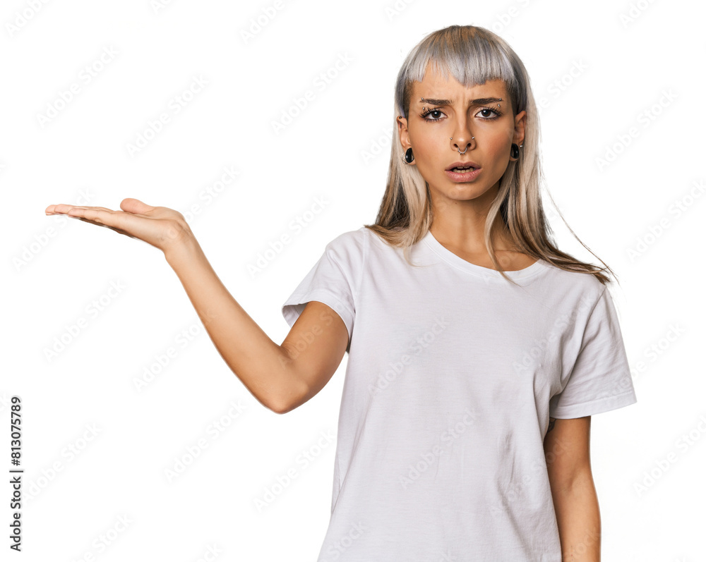 Young caucasian young woman in studio impressed holding copy space on palm. Young caucasian young woman in studio impressed holding copy space on palm.