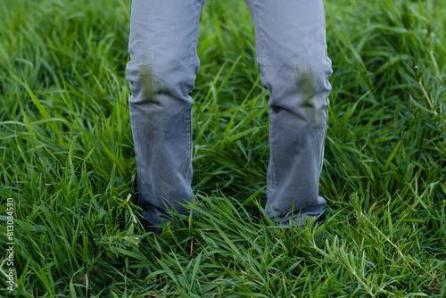 Dirty grass stains on clothes. An unrecognizable child with green knees on a green background. Spoiled clothes. Daily life dirty stain. outdoors. © HalynaRom