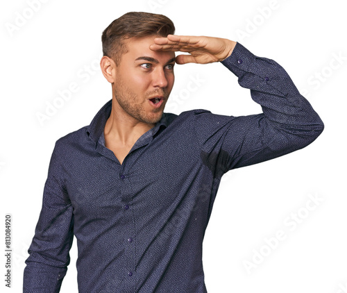 Young Caucasian man in studio looking far away keeping hand on forehead.