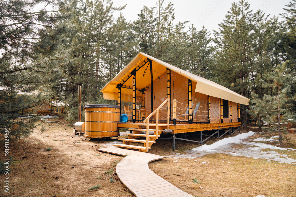 A glamping house with a swimming hot tub in a pine forest. A glamping house with a swimming hot tub in a pine forest.