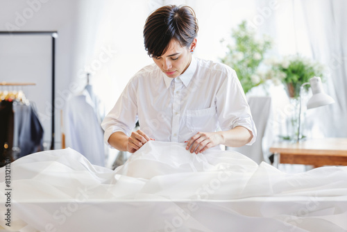 A young woman designer inspects the white fabric for any irregularities or imperfections with a critical eye. photo