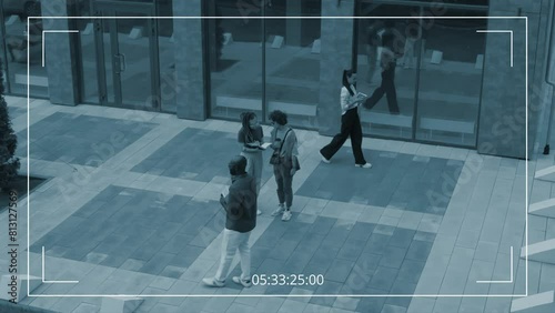 High angle security camera footage of diverse male and female corporate employees strolling, talking on mobile phone, discussing business issues next to office building aentrance photo