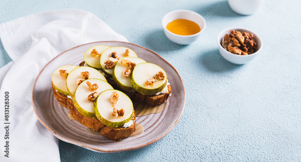 Appetizing sandwiches on rye bread with arugula, pear, honey and nuts on a plate web banner Appetizing sandwiches on rye bread with arugula, pear, honey and nuts on a plate web banner