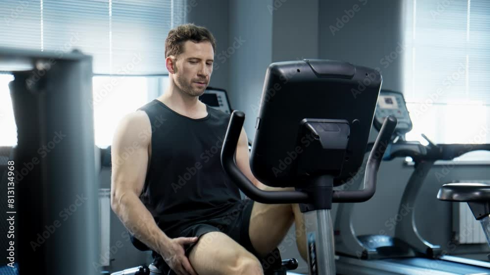 Handsome man doing cycling exercise in gym. Sporty man working hard while cycling on exercise bike. Working out on bike indoors. Healthy lifestyle and sport concept. 4K, UHD Handsome man doing cycling exercise in gym. Sporty man working hard while cycling on exercise bike. Working out on bike indoors. Healthy lifestyle and sport concept. 4K, UHD