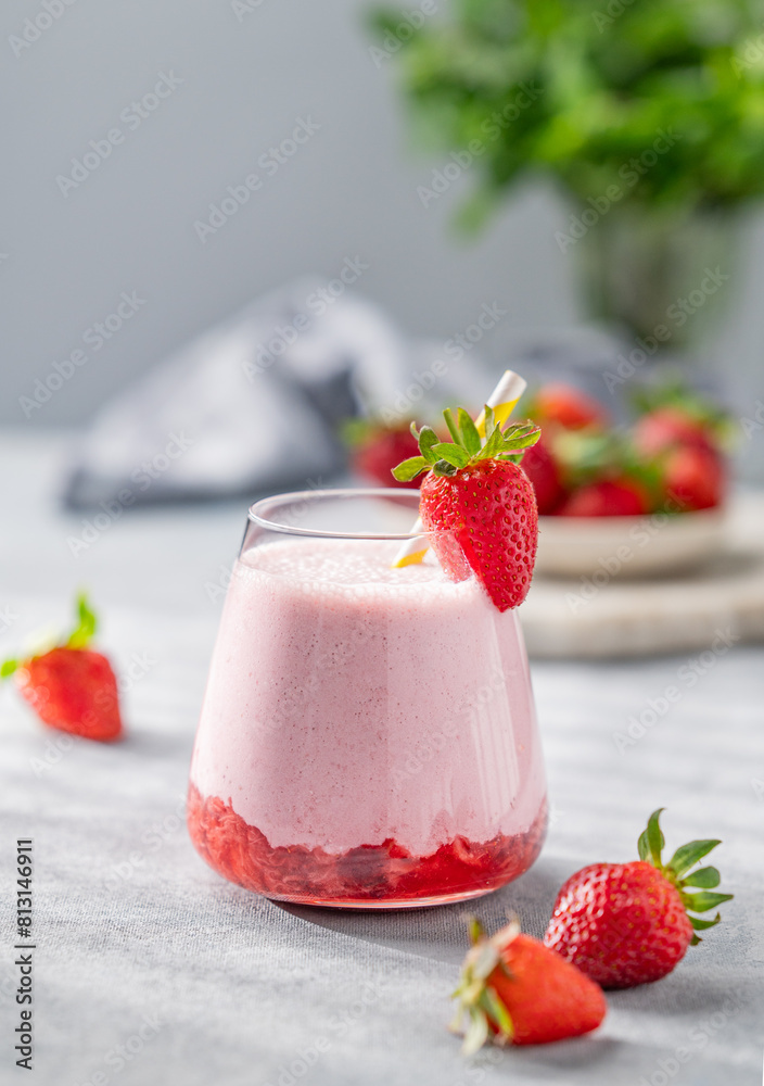 Strawberry milkshake or smoothie in a glass on a light background with fresh berries and shadows. Strawberry milkshake or smoothie in a glass on a light background with fresh berries and shadows.