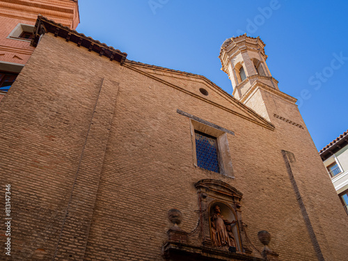 Vista de abajo arriba, de la fachada de una iglesia en Zaragoza con estatuas en la entrada y un campanario, viajando por España en verano de 2021 photo