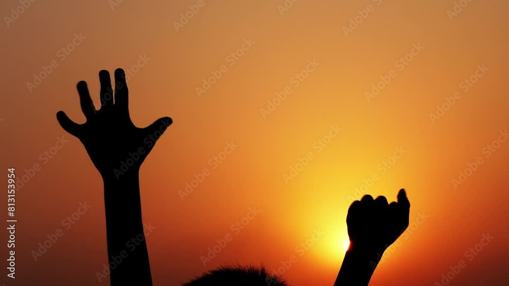 A child's hands clenching and unclenching against a background of yellow-orange light at sunset. A child's hands clenching and unclenching against a background of yellow-orange light at sunset.