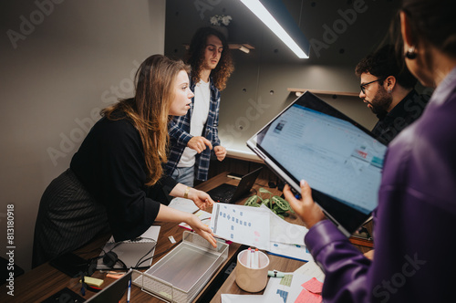 Focused business team in a heated discussion about a problematic project at a contemporary workspace. Detailed documents and digital tools in use.
