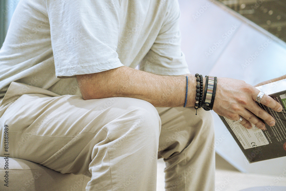 A boy dressed in white with bracelets and rings on his hand sits A boy dressed in white with bracelets and rings on his hand sits