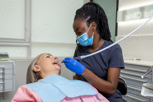 Dark-skinned female dentist working with the patient