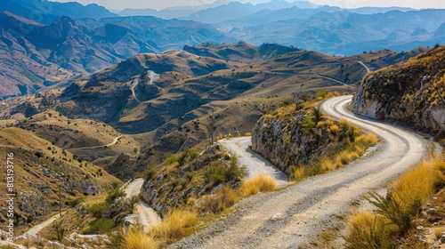 A winding mountain road disappearing into the horizon, offering a scenic drive through rugged terrain.