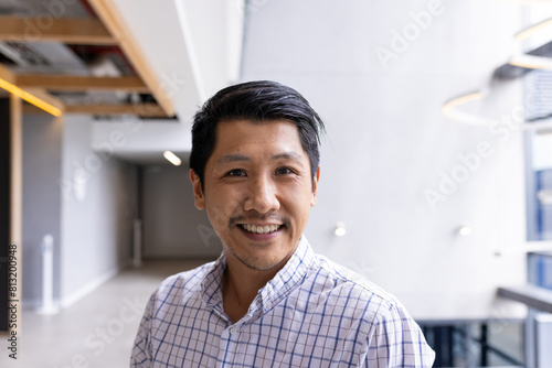 Asian male professional standing at office, smiling at camera