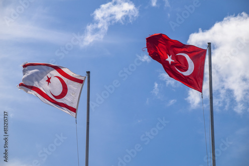 Turkey and Turkish Republic of Northern Cyprus flags waving in the blue and cloudy sky photo