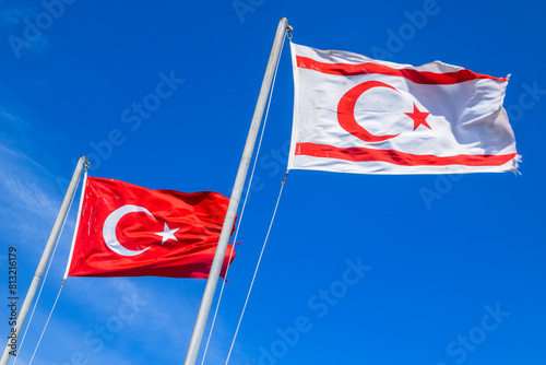 Turkey and Turkish Republic of Northern Cyprus flags waving in the blue and cloudy sky