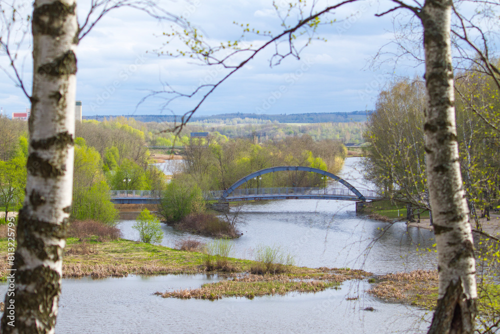 Fototapeta premium Sestroretsky public park and bridge over river Sestra at spring in Klin town, Moscow region, Russia 