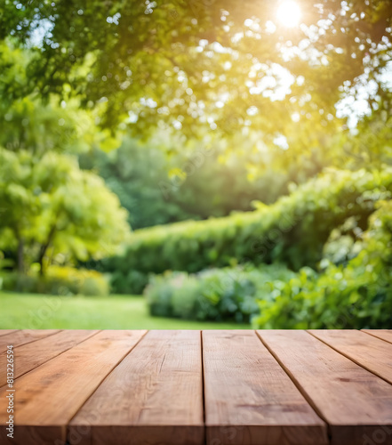 Wooden table top on blur background of green garden with bokeh sunlight. High quality photo 